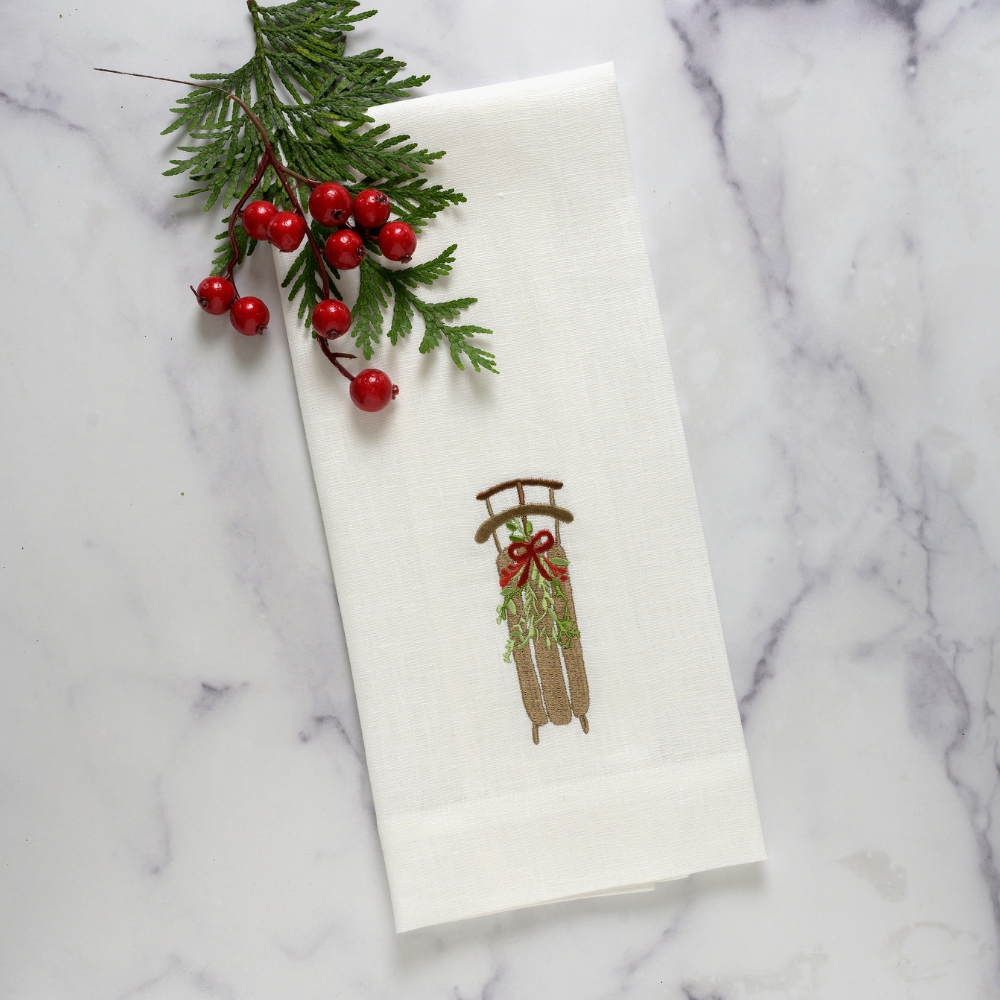 Add a touch of winter wonderland to your kitchen or bath with our 100% European linen Christmas sled towel. The beautiful embroidery, featuring a winter sled with greenery and a red bow, will elevate any room in your home. 17x29" with a tab for hanging, this Italian-made towel is versatile and sure to impress.