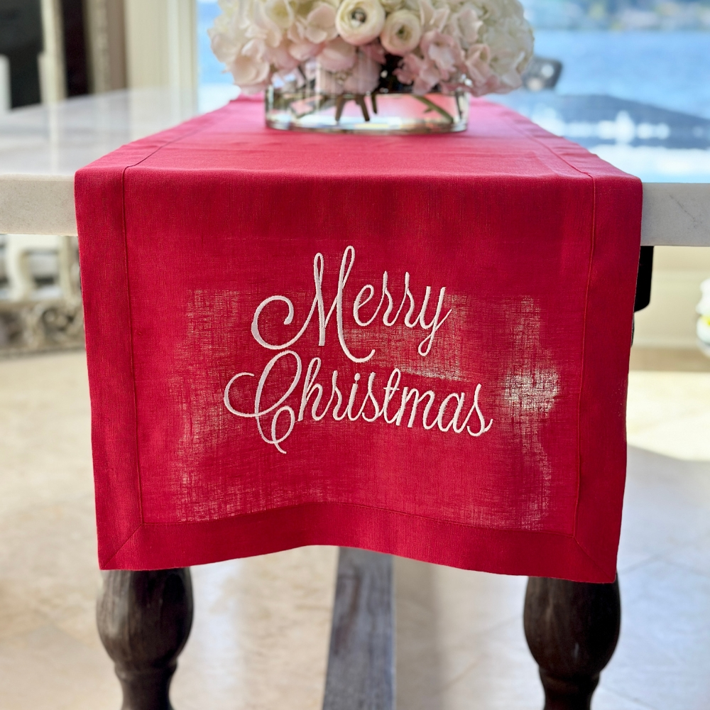 Expertly crafted from 100% embroidered European linen, this 108" long table runner adds a touch of elegance to any dining table or side board. Made in Italy, it features the festive phrase "Merry Christmas" making it perfect for adding holiday cheer to your dining space.