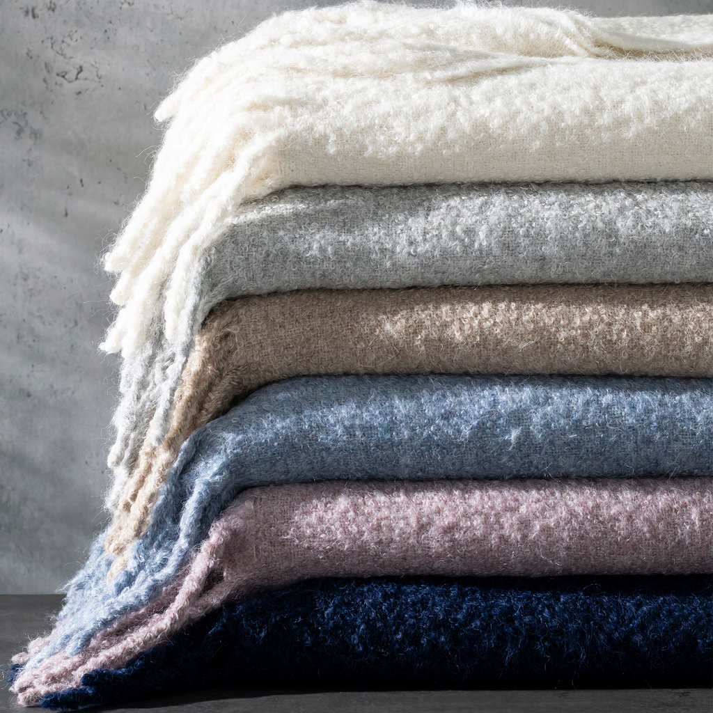 Experience ultimate comfort with Matouk's Poncho Throw. This versatile piece can be used as a throw blanket or a cozy coat, thanks to its weighted and woven Suri alpaca bouclé and wool blend fabric. Stay warm and stylish with the hand-knotted fringed edges. Made in Peru. OEKO-TEX Standard 100 Certified.