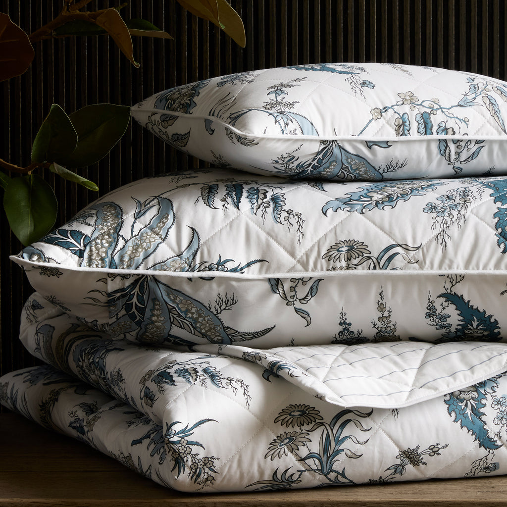 Apolline Quilt + Shams, designed by Schumacher. This botanical print evokes classic sophistication and grace. Sewn from 100% Egyptian cotton percale, boasting a Mediterranean blue floral pattern and silvery grey hues. Large diamond quilting and white piped edges add an exquisite touch.