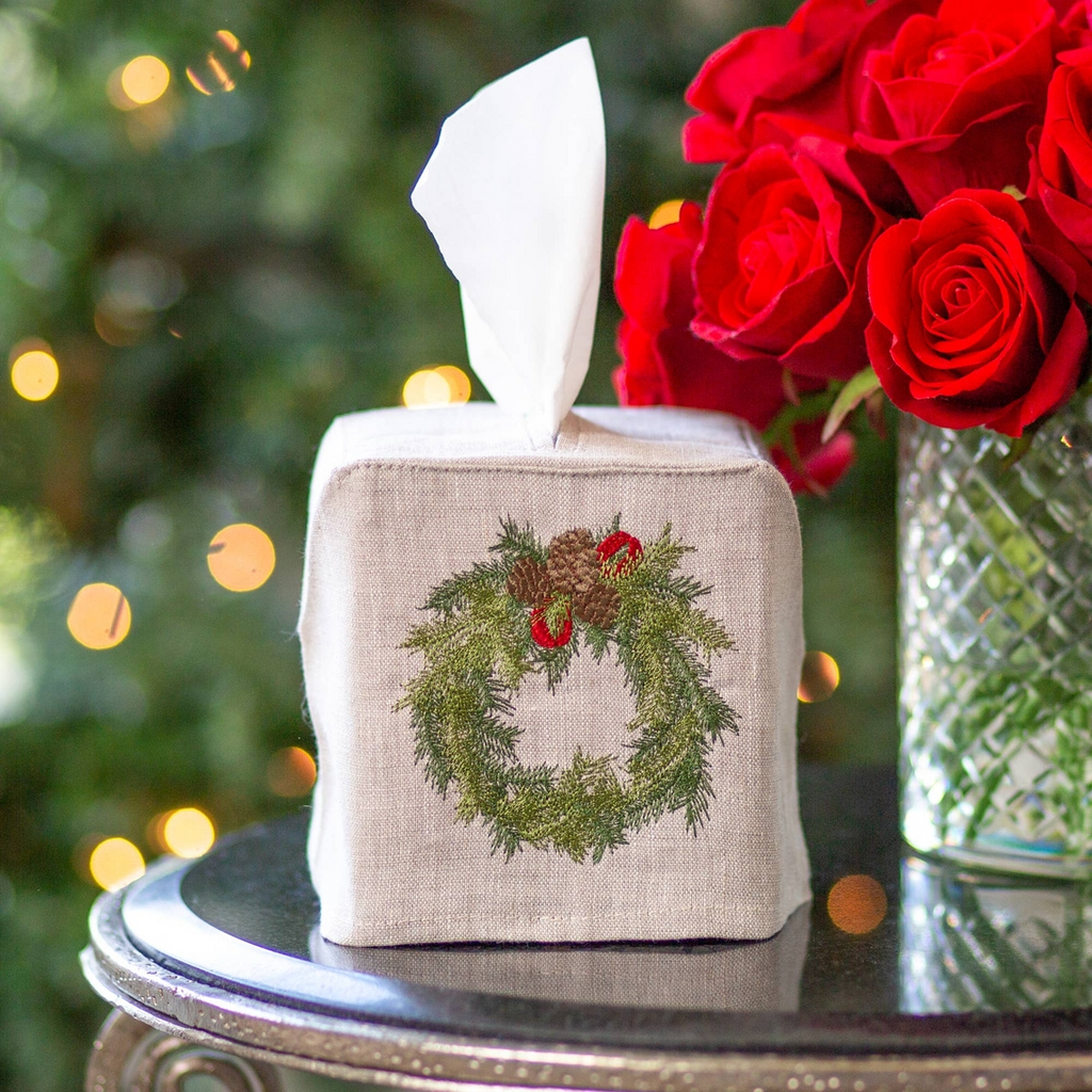 Crown Linens Boxwood Wreath Tissue Box Cover. Crafted from 100% European flax linen, this luxurious tissue cover features intricate embroidery of a wreath, pinecones and red ribbons. Perfect for dressing up unsightly tissue boxes, this embroidered cover adds a touch of elegance to any room. Made in Ukraine.