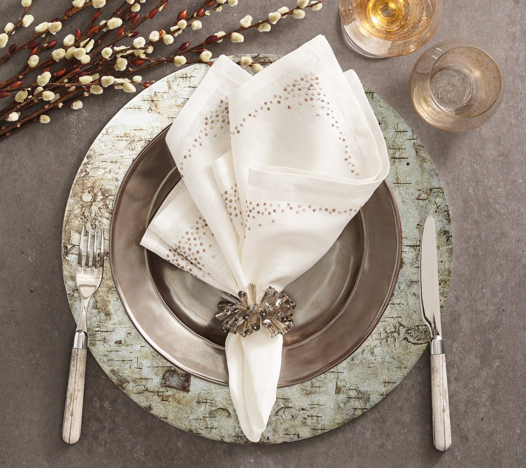 Elevate your table setting with the Chalet Placemat in Natural & Silver from Kim Seybert. The rustic birch bark image transferred onto a shimmering silver foil lacquered surface adds a touch of nature-inspired charm to any meal. Perfect for country or upscale settings, this placemat adds sophisticated, bucolic elegance to your dining experience.