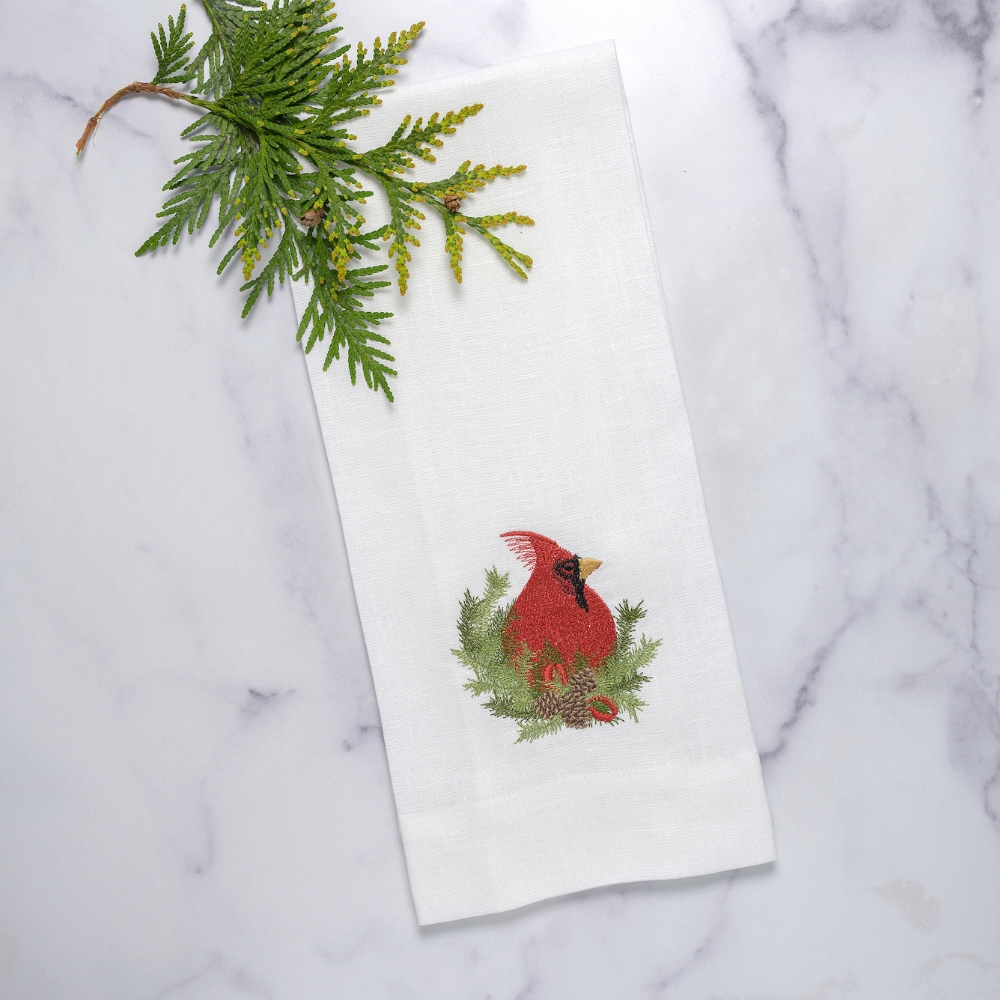 Add a touch of elegance to your kitchen or bathroom with the Christmas Cardinal Towel. Made from 100% embroidered European linen, this guest towel features a red cardinal and winter greenery design. Measuring 17x29", it's perfect for any part of your home. Made in Italy.