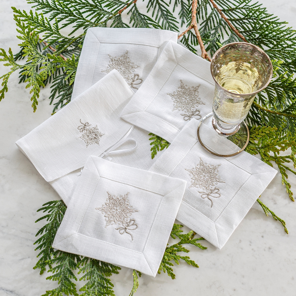 Add a touch of elegance to your table with our Snowflake Cocktail Napkin Set. Made from 100% European white linen, each napkin is delicately embroidered with a platinum "Snowflake" emblem. Perfect for entertaining or as a thoughtful gift, each set comes in a luxurious linen pouch. Made in Italy.