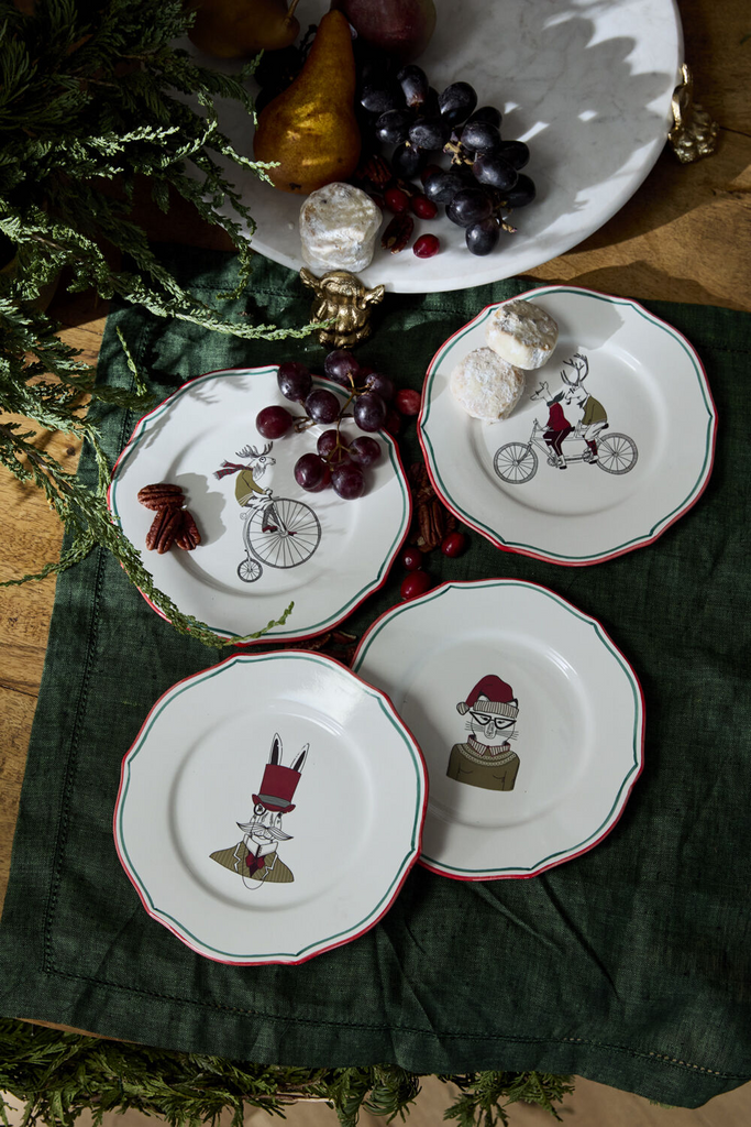 The E+E Cocktail Plate Collection by Jessica Heimstra adds festive flair to your gatherings. These quirky ceramic plates feature hand-painted red and green rims and holiday-themed artwork decals, perfect for a playful holiday bar or dessert table. Food-safe and fun!